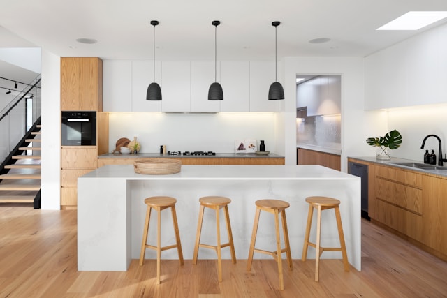 Minimalist modern kitchen with white worktops and light brown bar stools