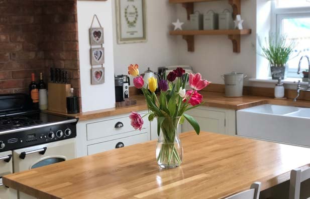 a counter with butcher block worktops and flowers in a vase on top