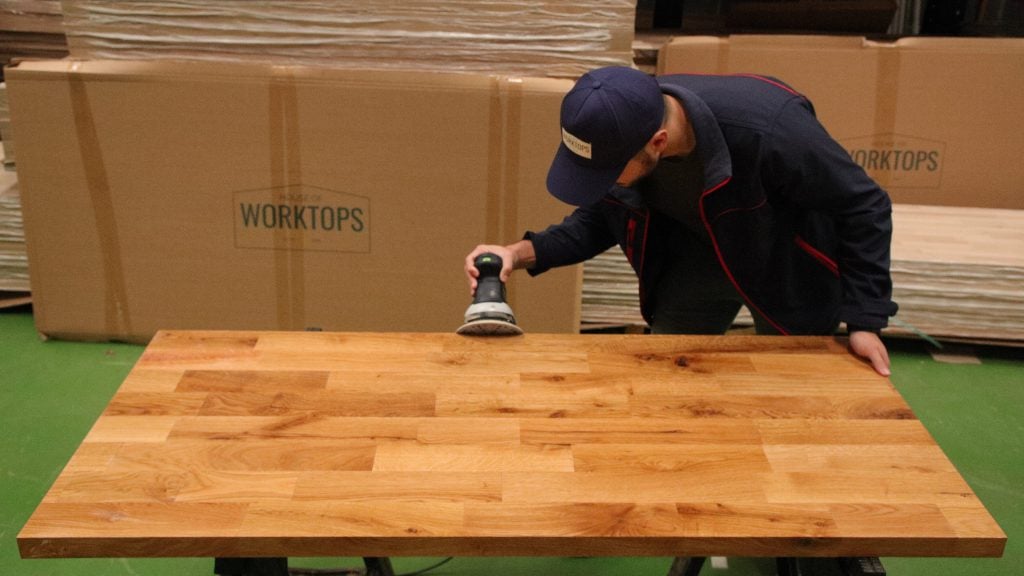 DIYer sanding an oak worktop using an orbital sander